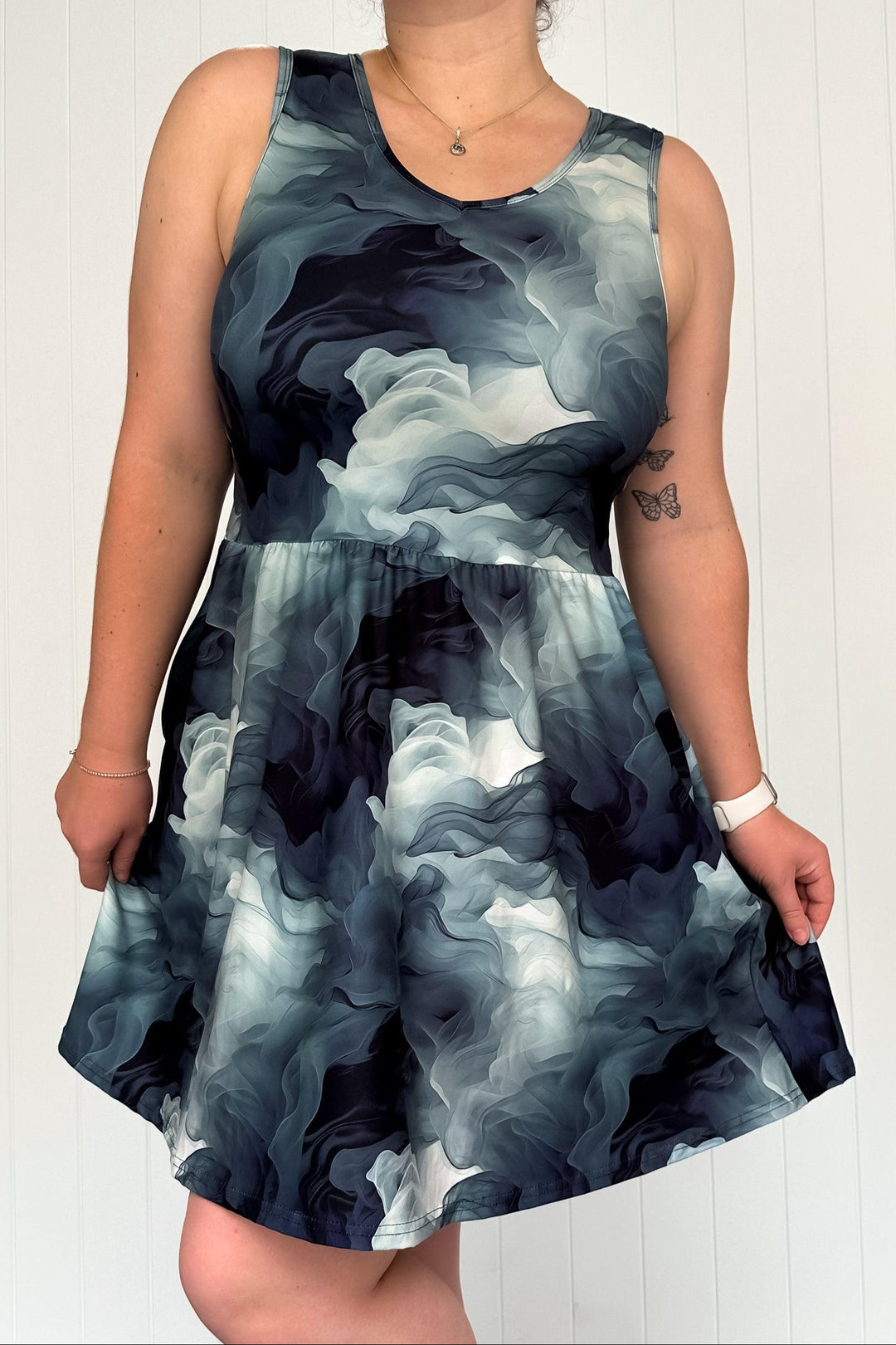 A sleeveless mini dress with a smoky abstract pattern in shades of gray and white, featuring a round neckline and side pockets.