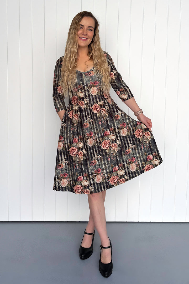 Woman wearing a floral dress against a white wall