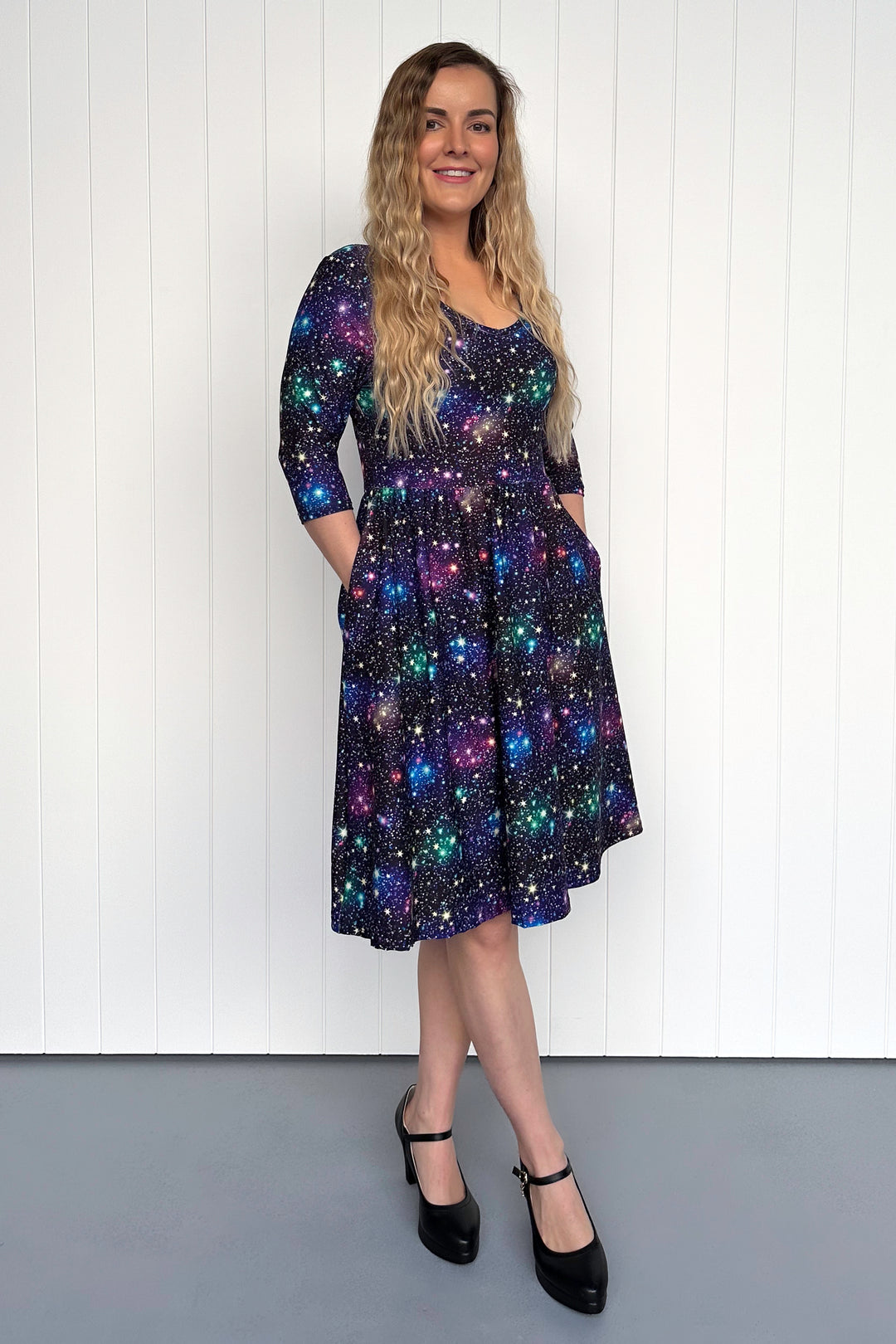 Woman wearing a dark dress with colorful star pattern against a white background