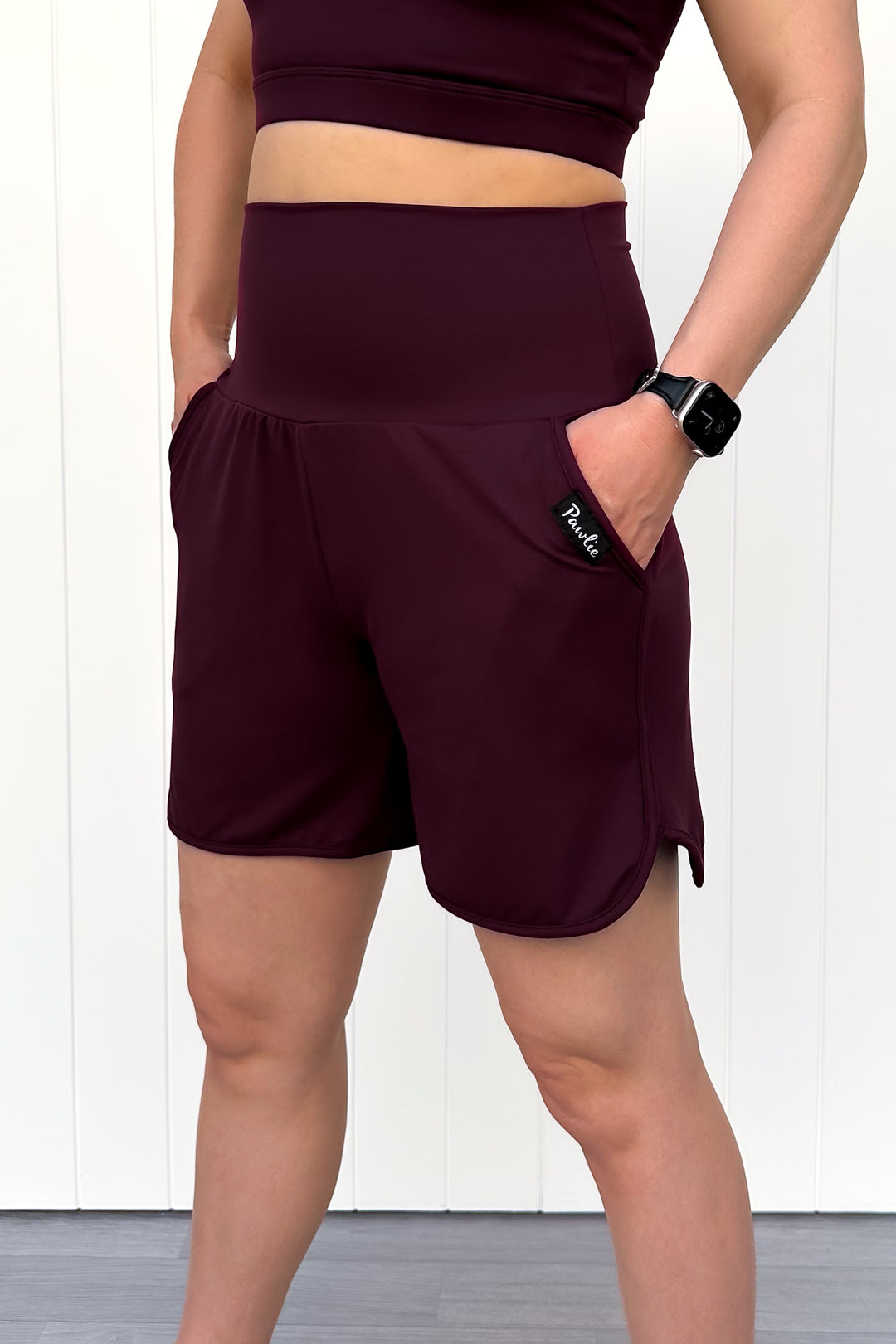 Person wearing maroon athletic shorts with a white background
