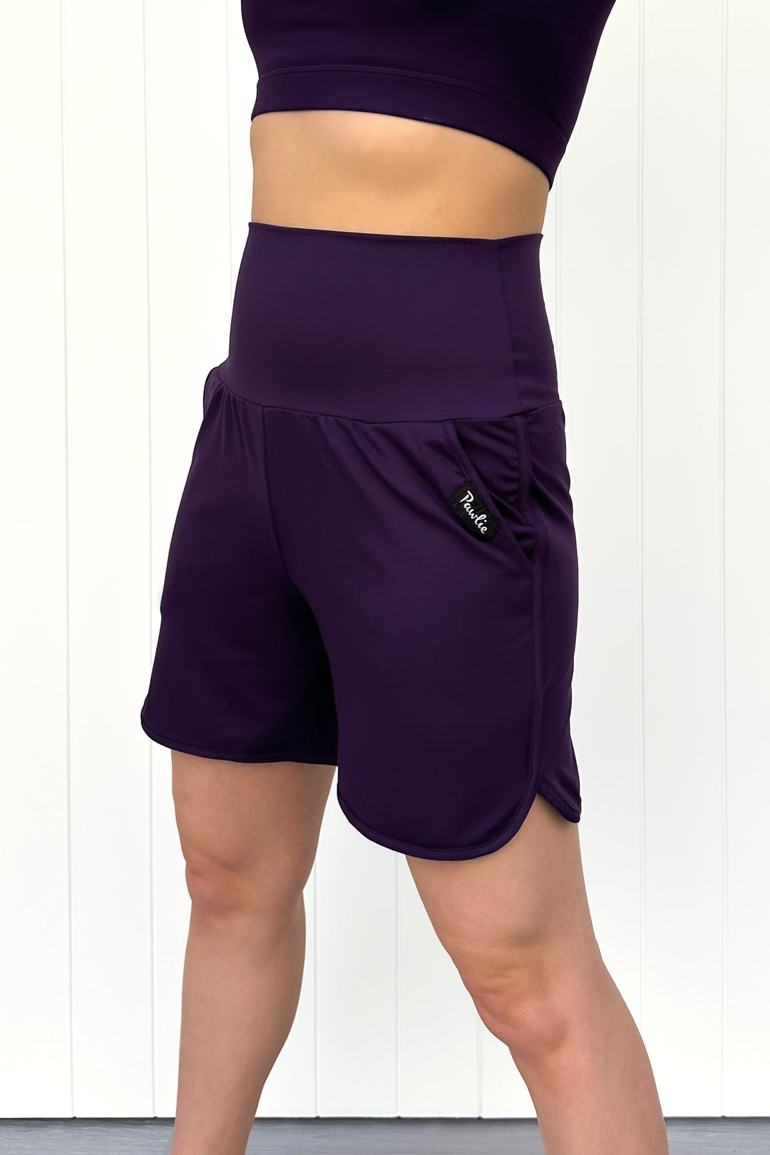 Purple athletic shorts worn by a person on a white background