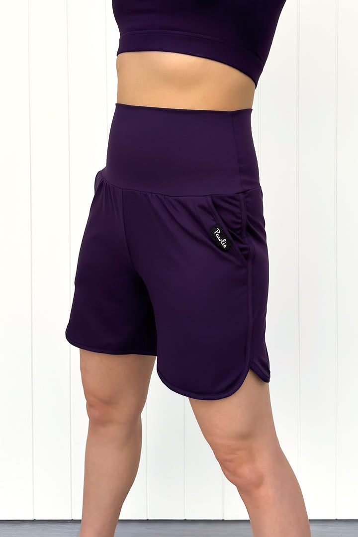 Purple athletic shorts worn by a person on a white background