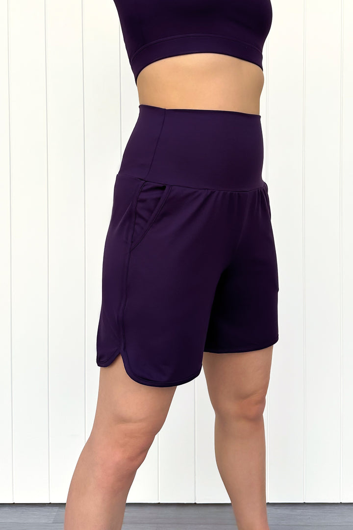 Person wearing purple athletic shorts and top on a white background